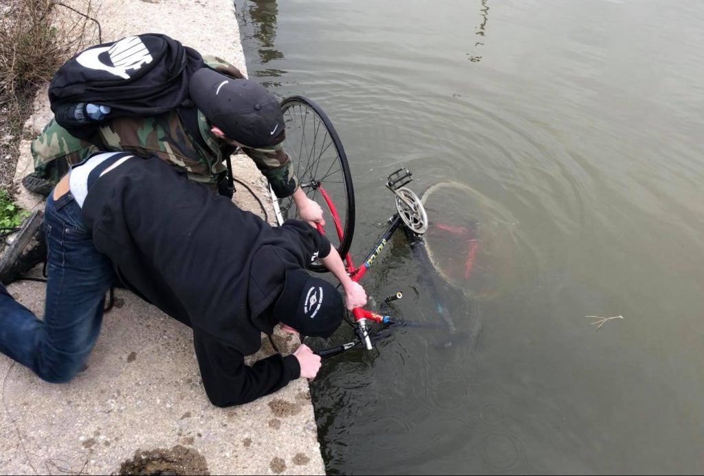 Doi căutători de comori trag o bicicletă din râu
