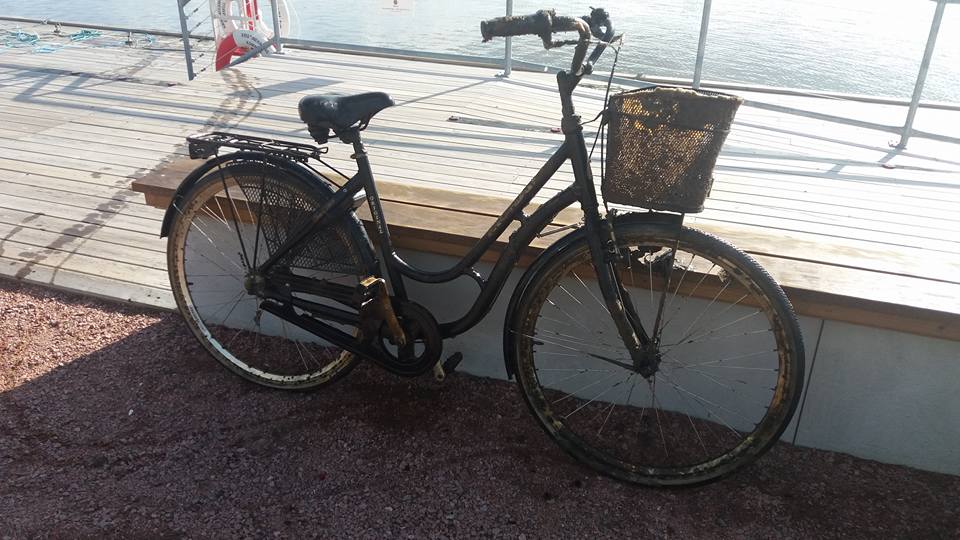 Bicicletă la mal, sprijinită de o bancă