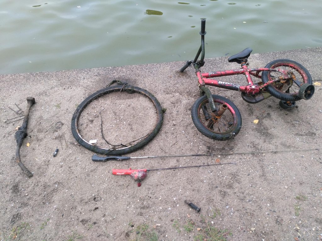 Bicicletă de copii, roată și undițe pe un mal pietros